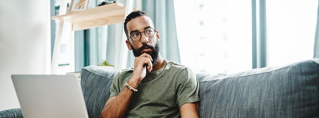 Image of black man pondering something while sitting on the couch