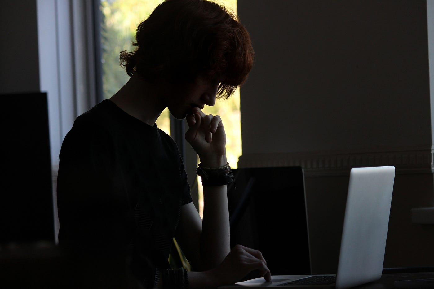 Dark image of a boy on his laptop.