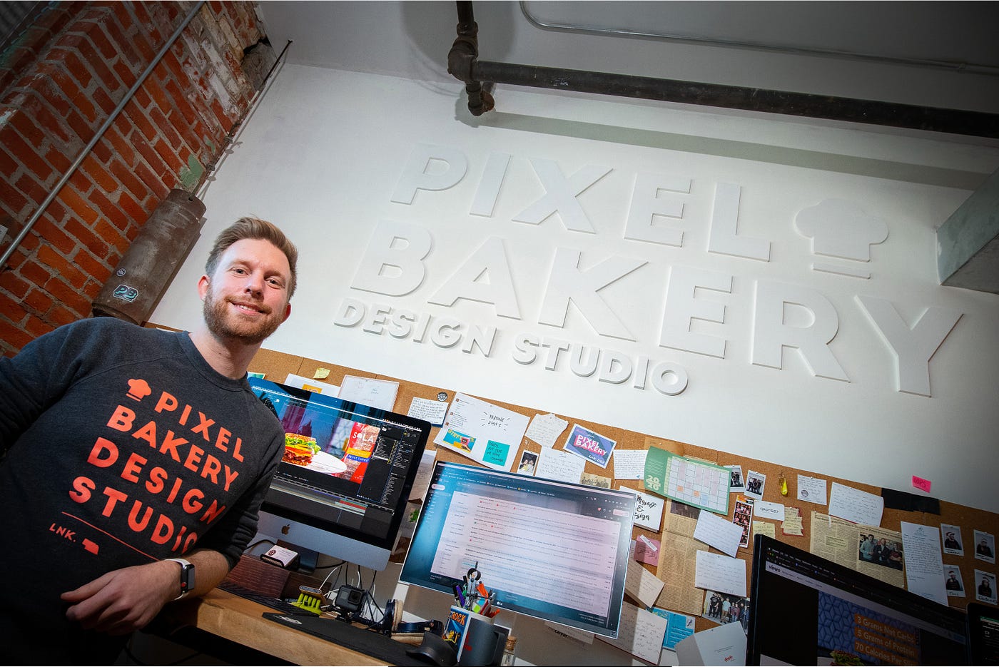 Jordan poses in front of computers inside Pixel Bakery