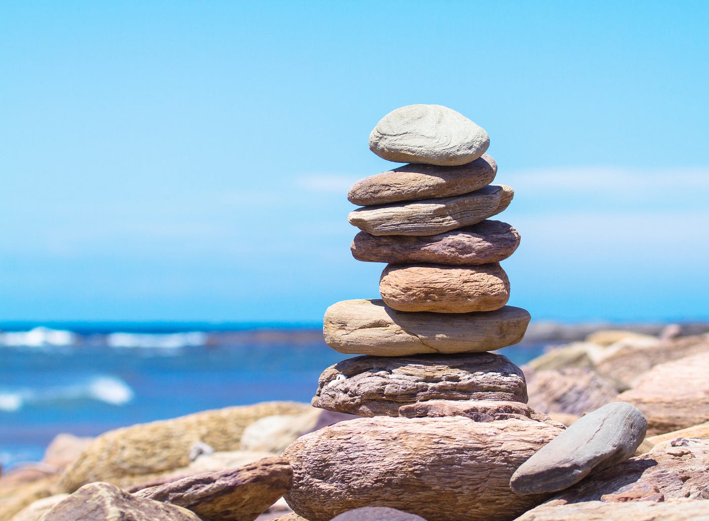 Picture of a beach with some rocks stacked up in a vertical pile