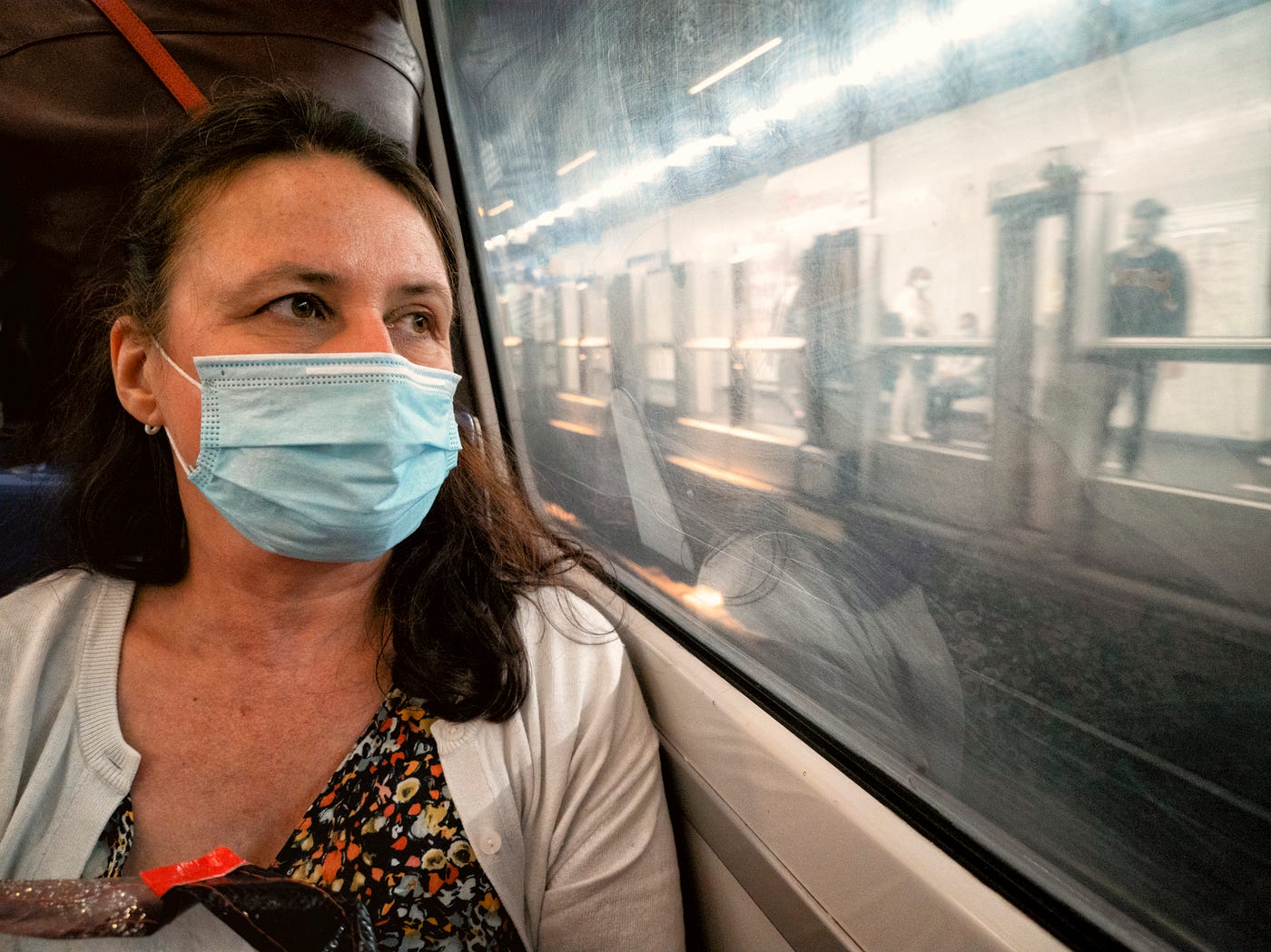 Woman riding train while wearing a face mask.