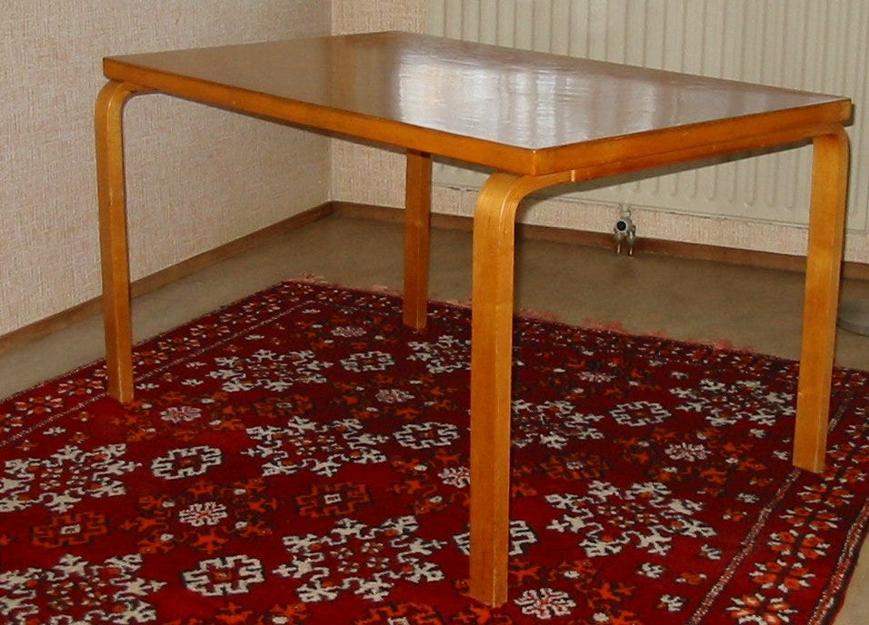 A low wooden table placed at a slant in the corner of a room next to a radiator