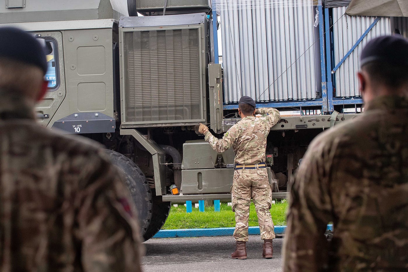 A soldier ubloads dividing screens from a lorry as colleagues stand ready to help