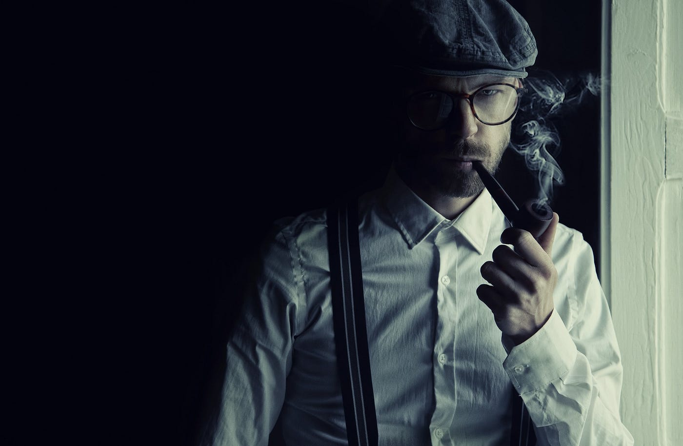 Young man in suspenders smokes a pipe thoughtfully.