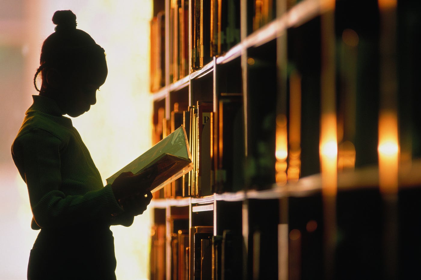 Young Black girl reads a book in school library.
