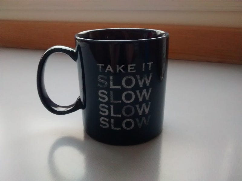 blue mug on counter reads “take it slow”