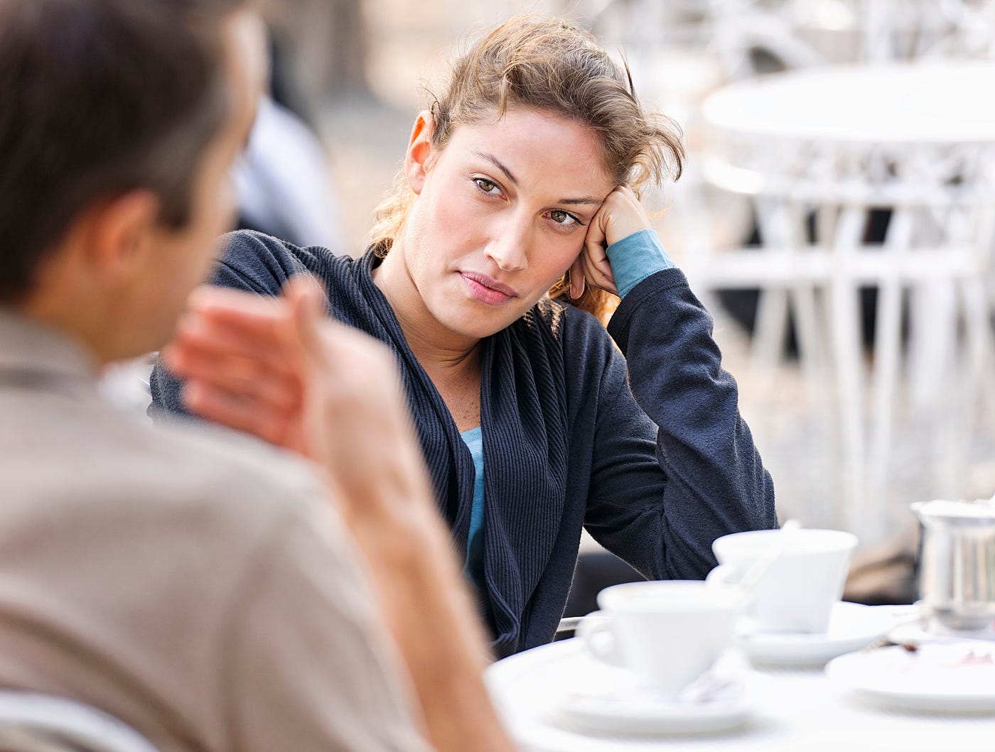 A photo of a slightly disgruntled woman looking at a man talk, waiting for him to finish.