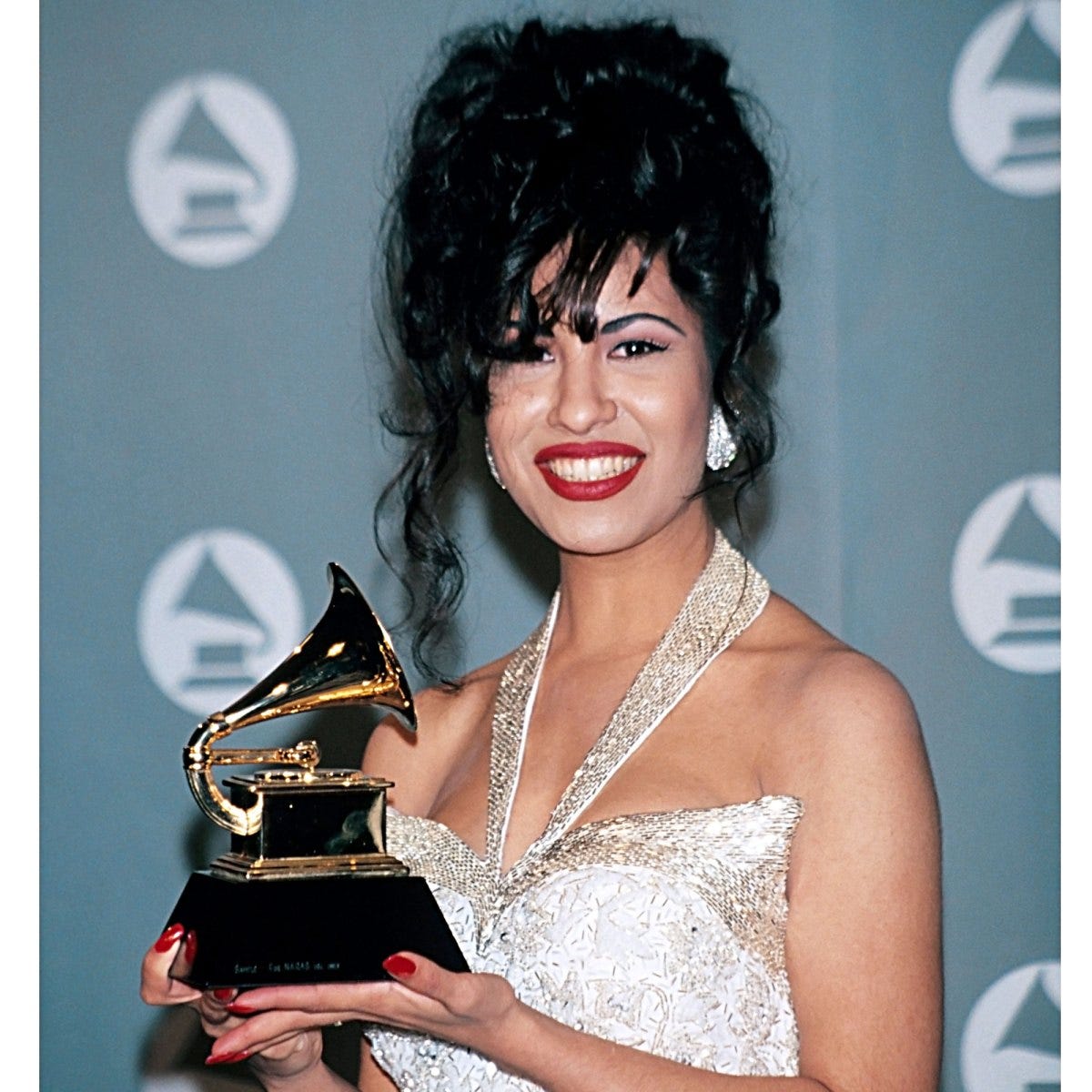 Selena on a red carpet holding a Grammy award