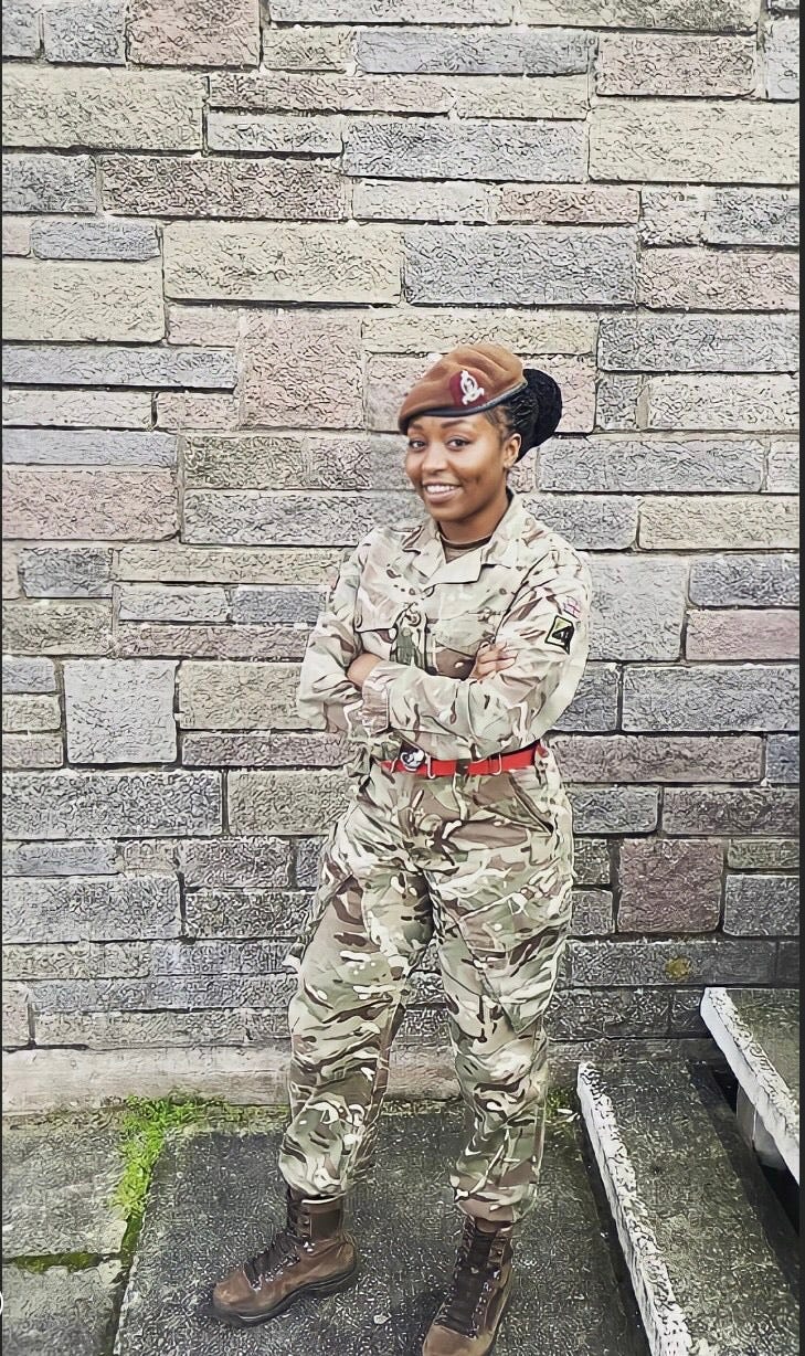 A woman in Army uniform stands in front of a wall