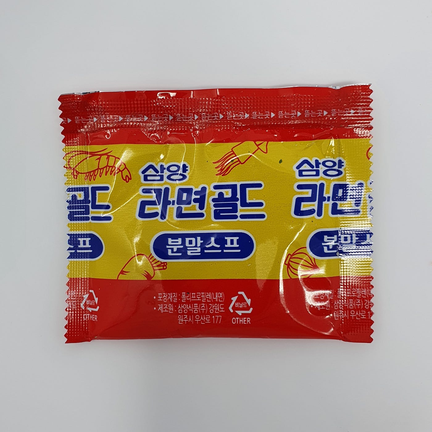 The powdered soup packet from a cup of Samyang Ramen Gold.