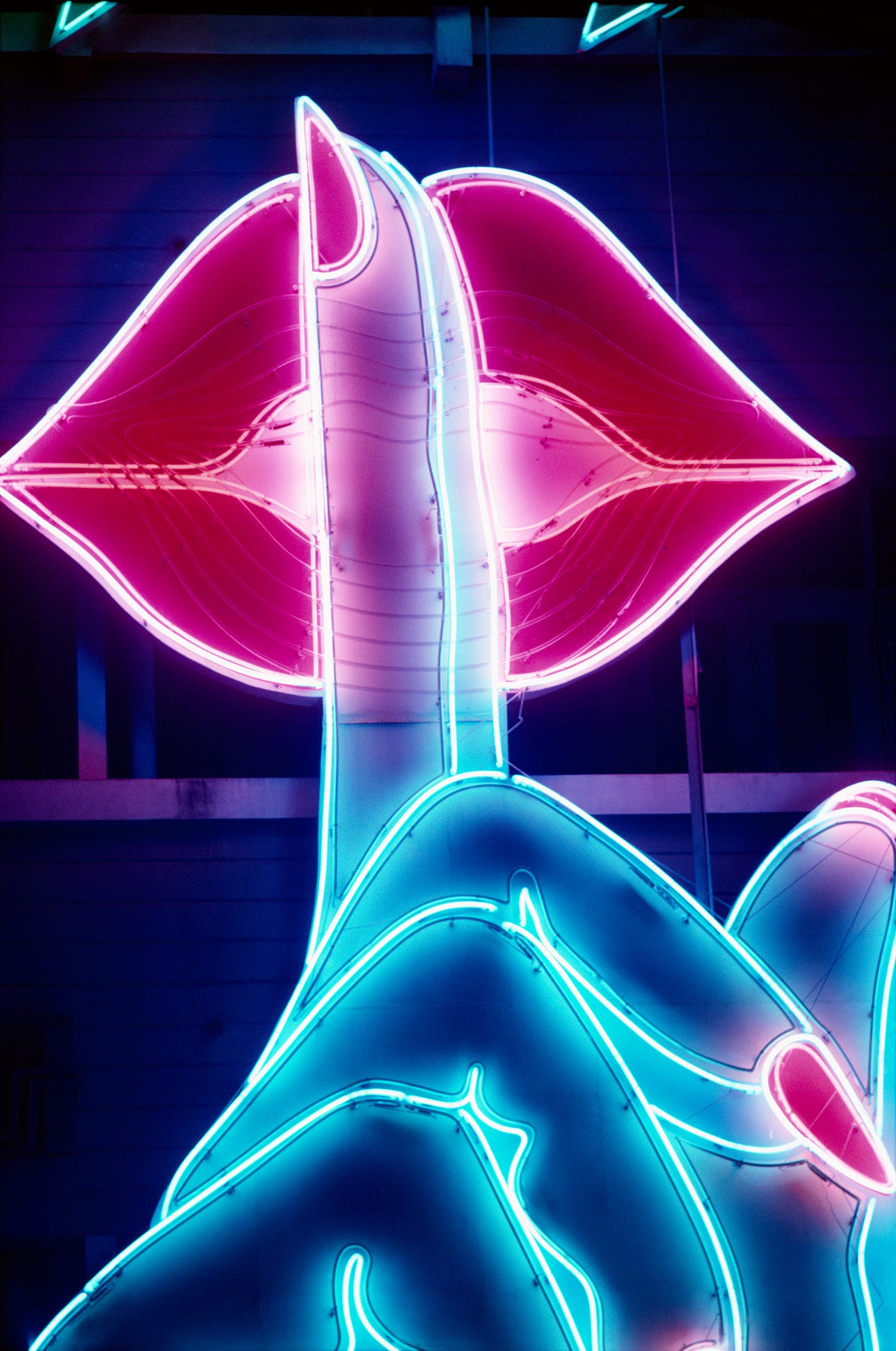 Neon signage of a finger in a hush motion over the lips