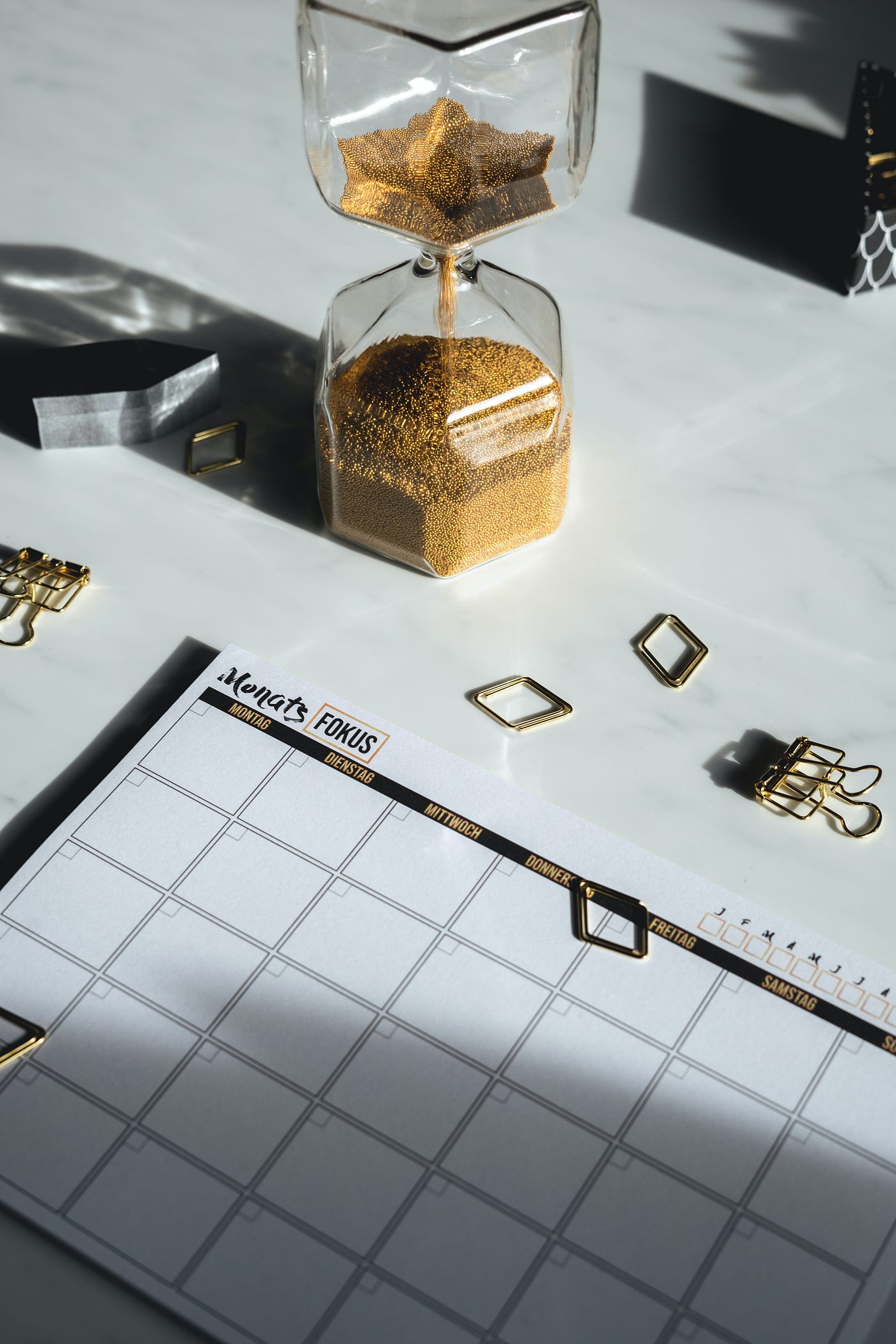 Desktop with blank calendar, hourglass, paper clips