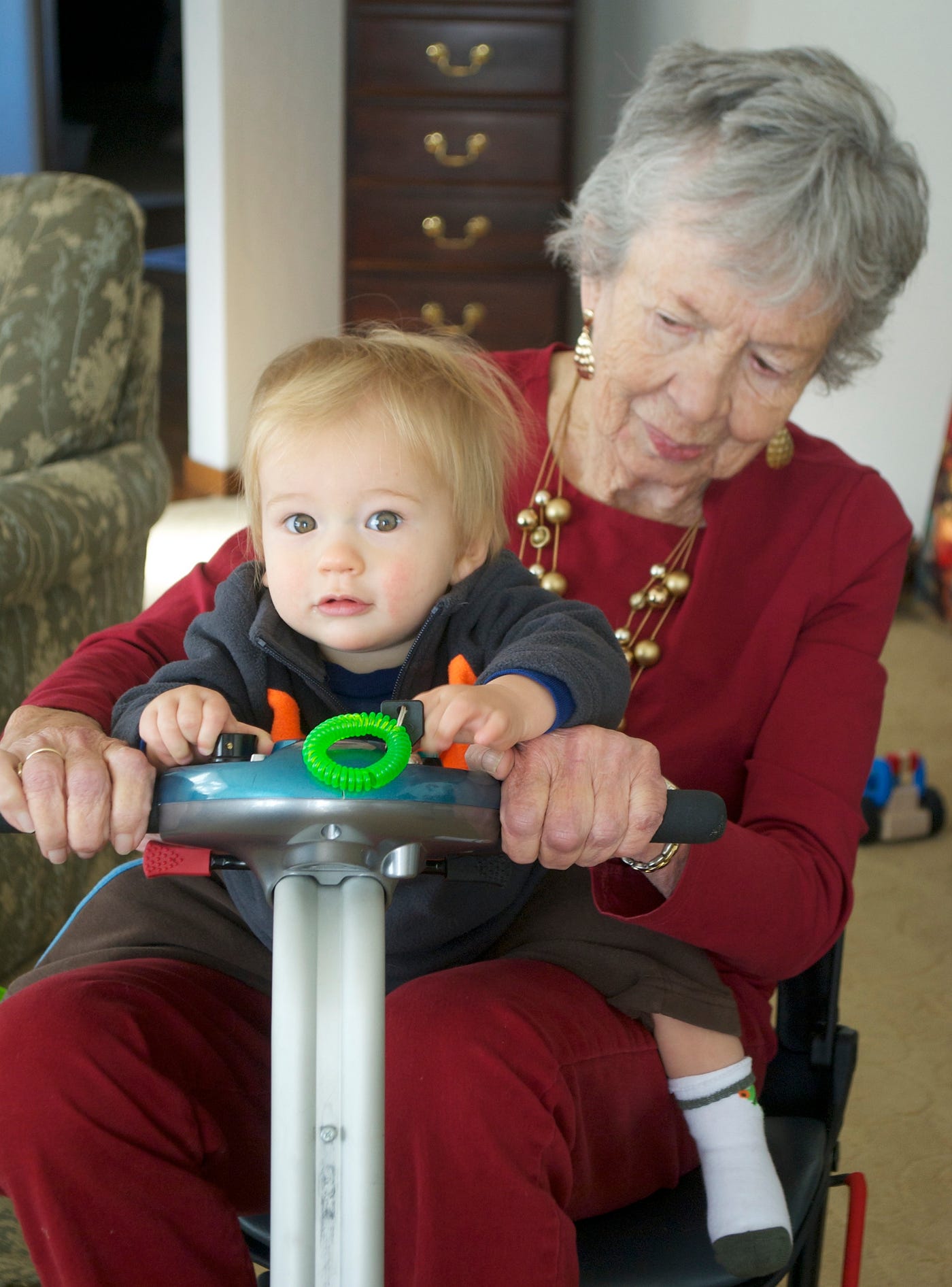 Grandma holding her great-grandson on a scooter