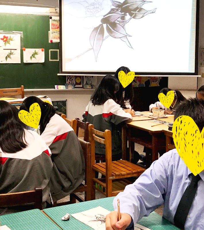 Students learning ink wash painting techniques from the comfort of their tables.