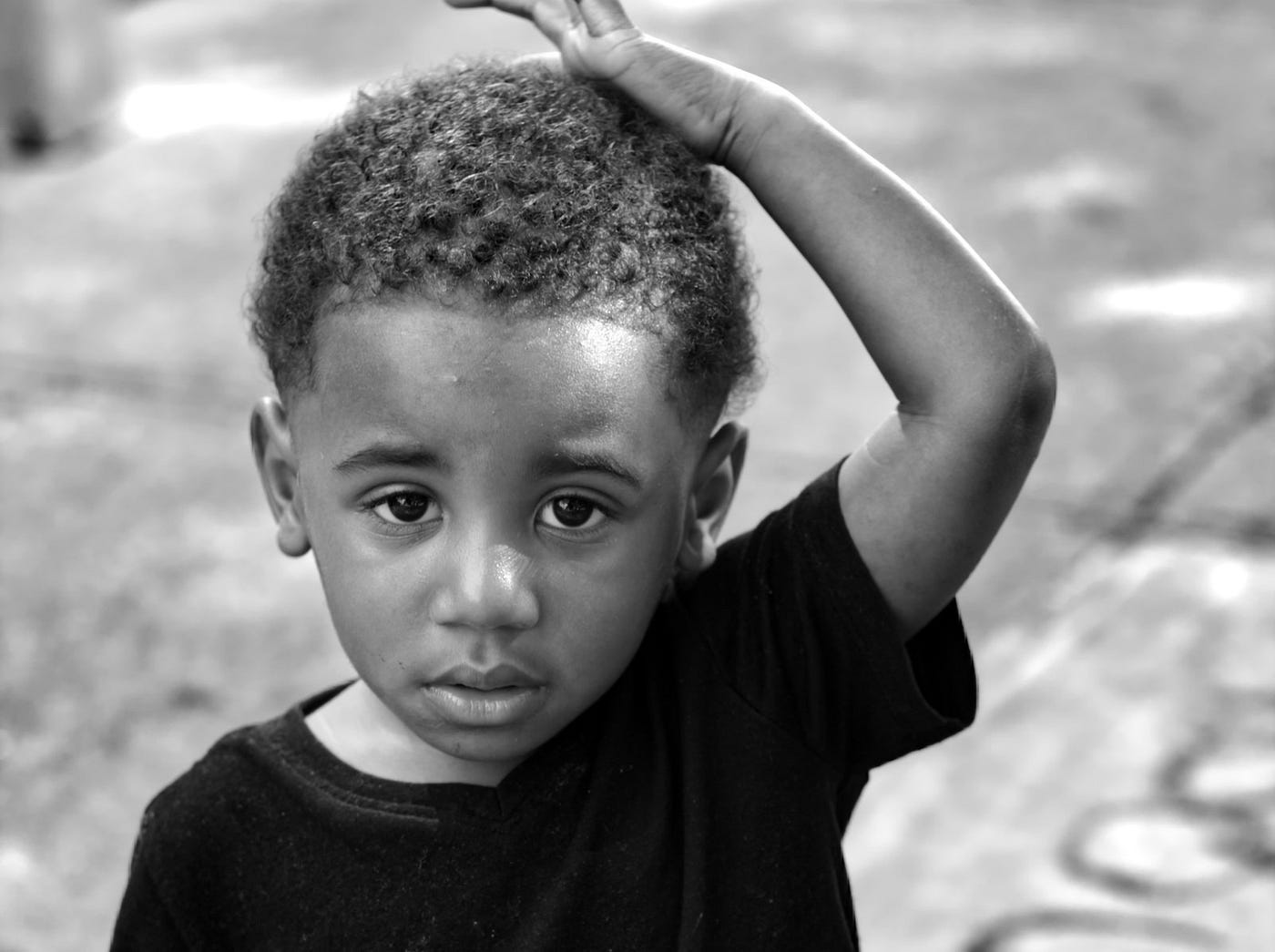 Black and white photo of young boy with hand on head.