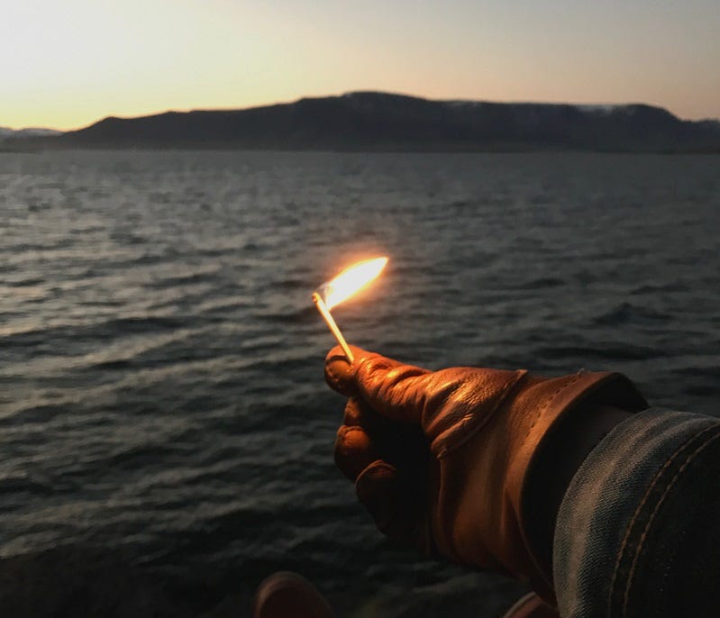 A burning match stick held in front of a lake — to illustrate why water does not burn