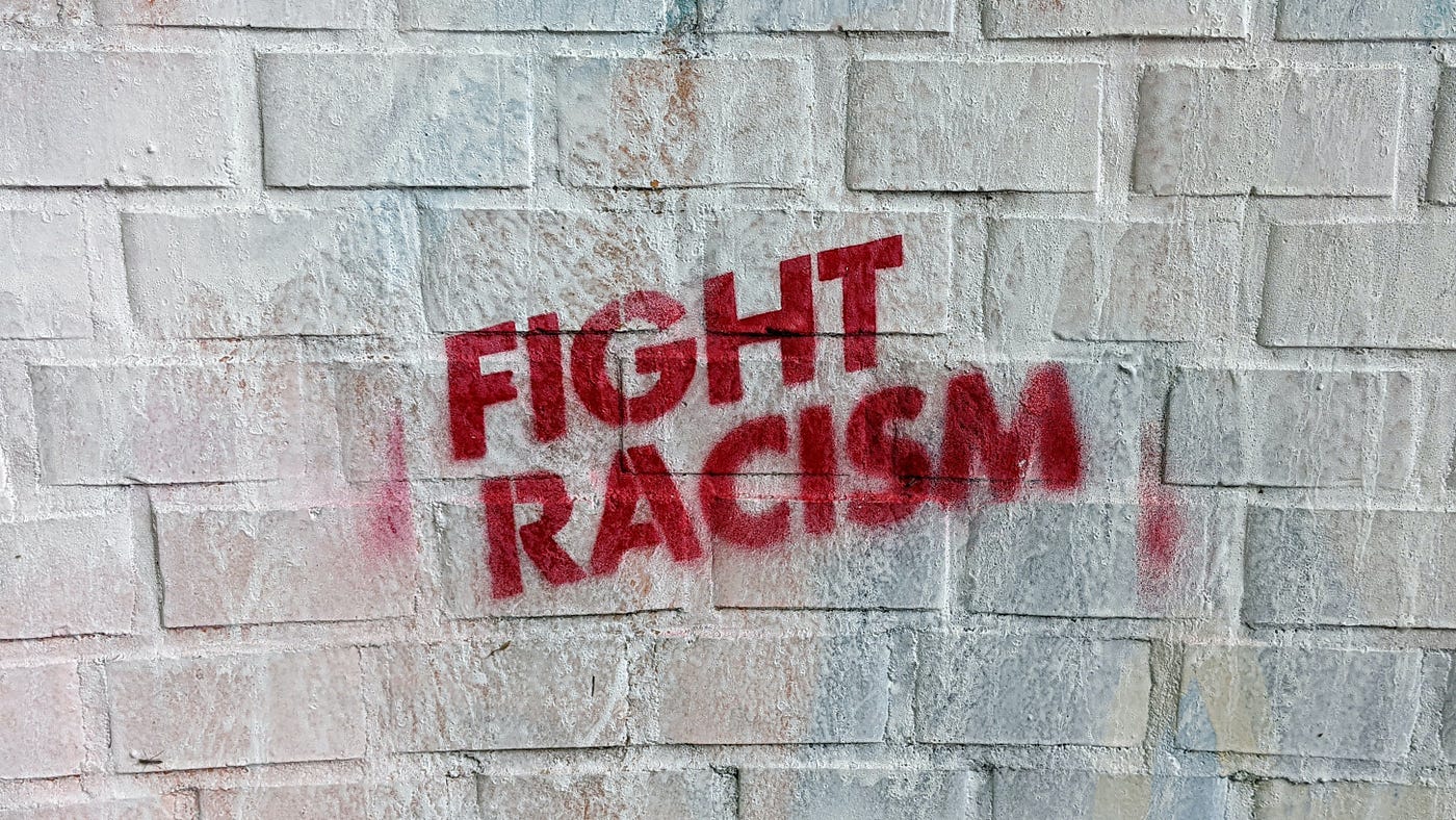 The words: FIGHT RACISM, in all capital, red letters on a white brick wall.