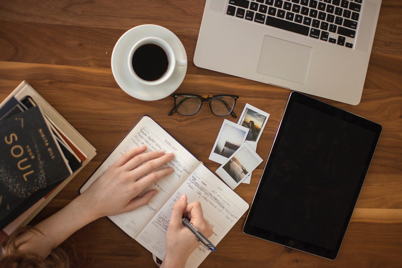 a woman making notes with a cup of coffee and laptop on the desk