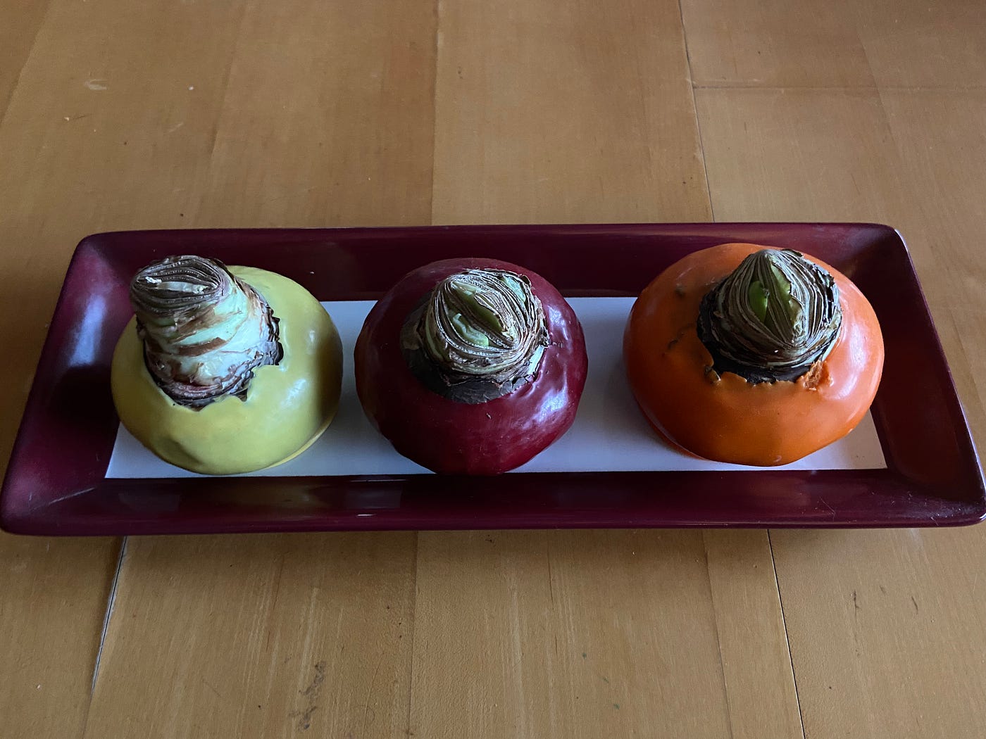 Photo of three Giant Amaryllis waxed bulbs: yellow, red and orange.