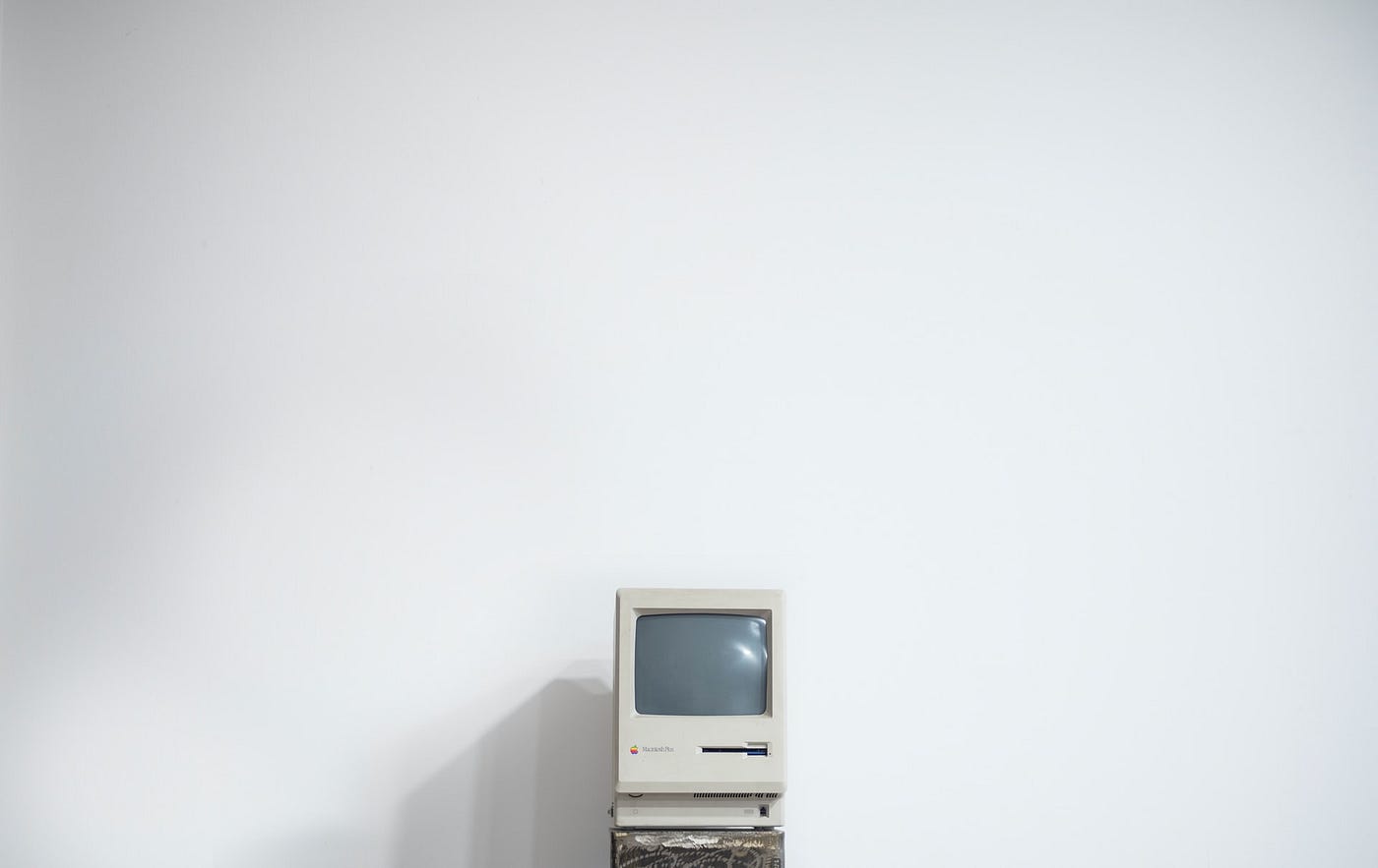 An antique computer set against a white wall.