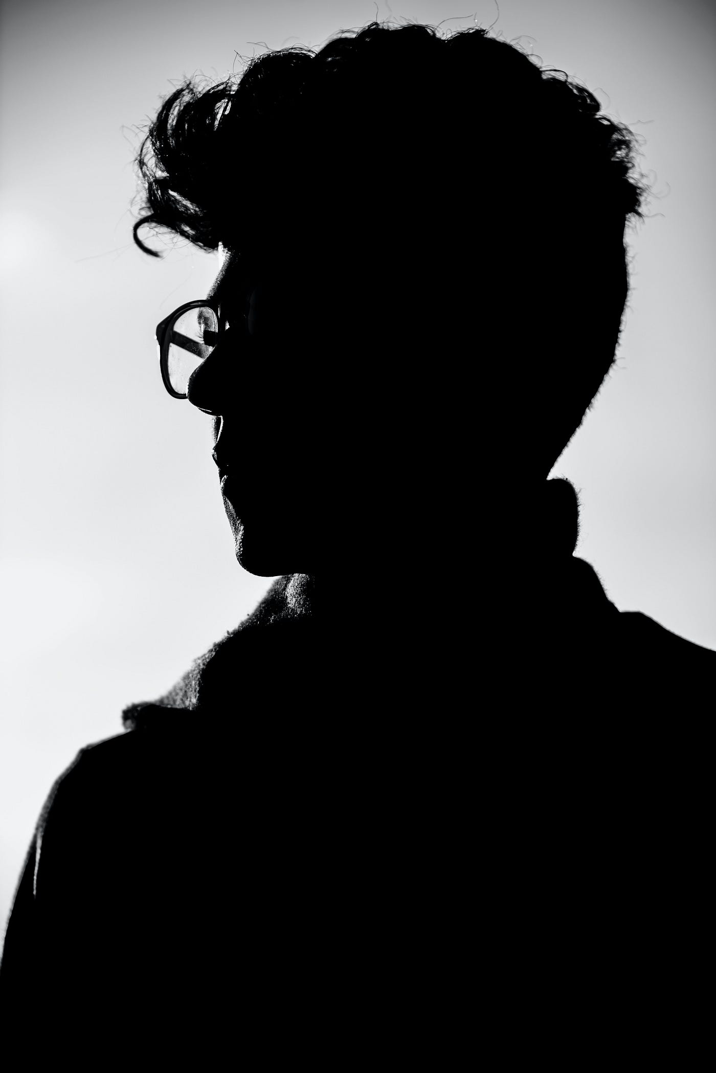 Silhouette of racially and gender ambiguous person staring off in introspection