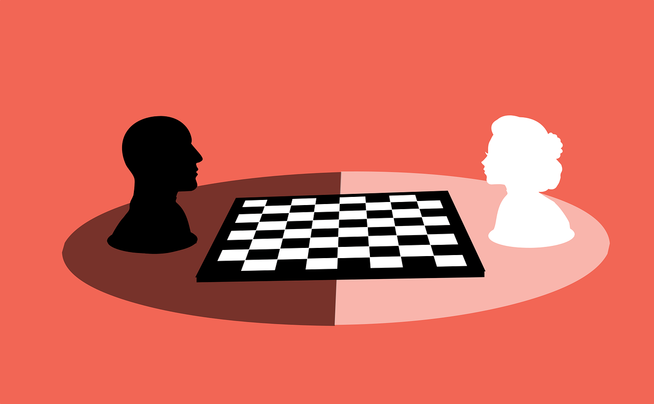 Man and woman sitting on opposite sides of chessboard.