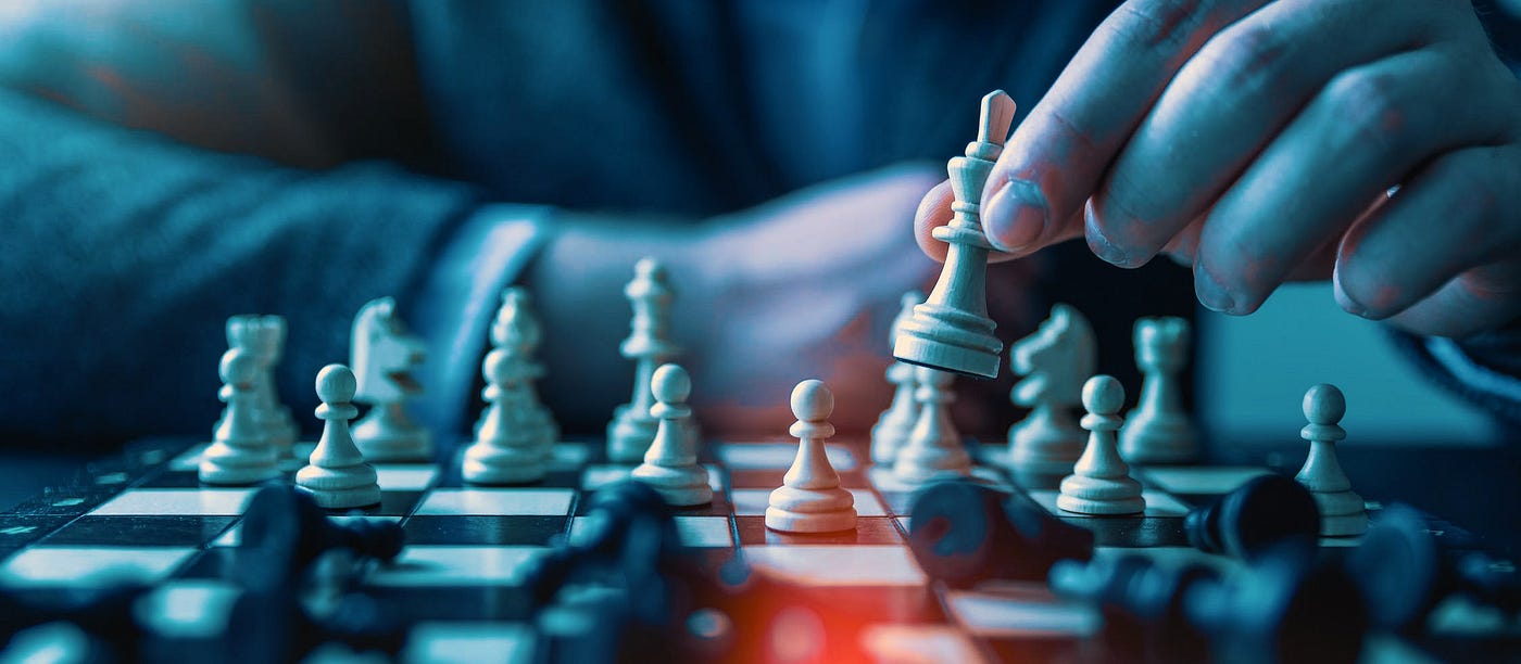 A chess player moving a white piece towards a slew of toppled over black pieces.