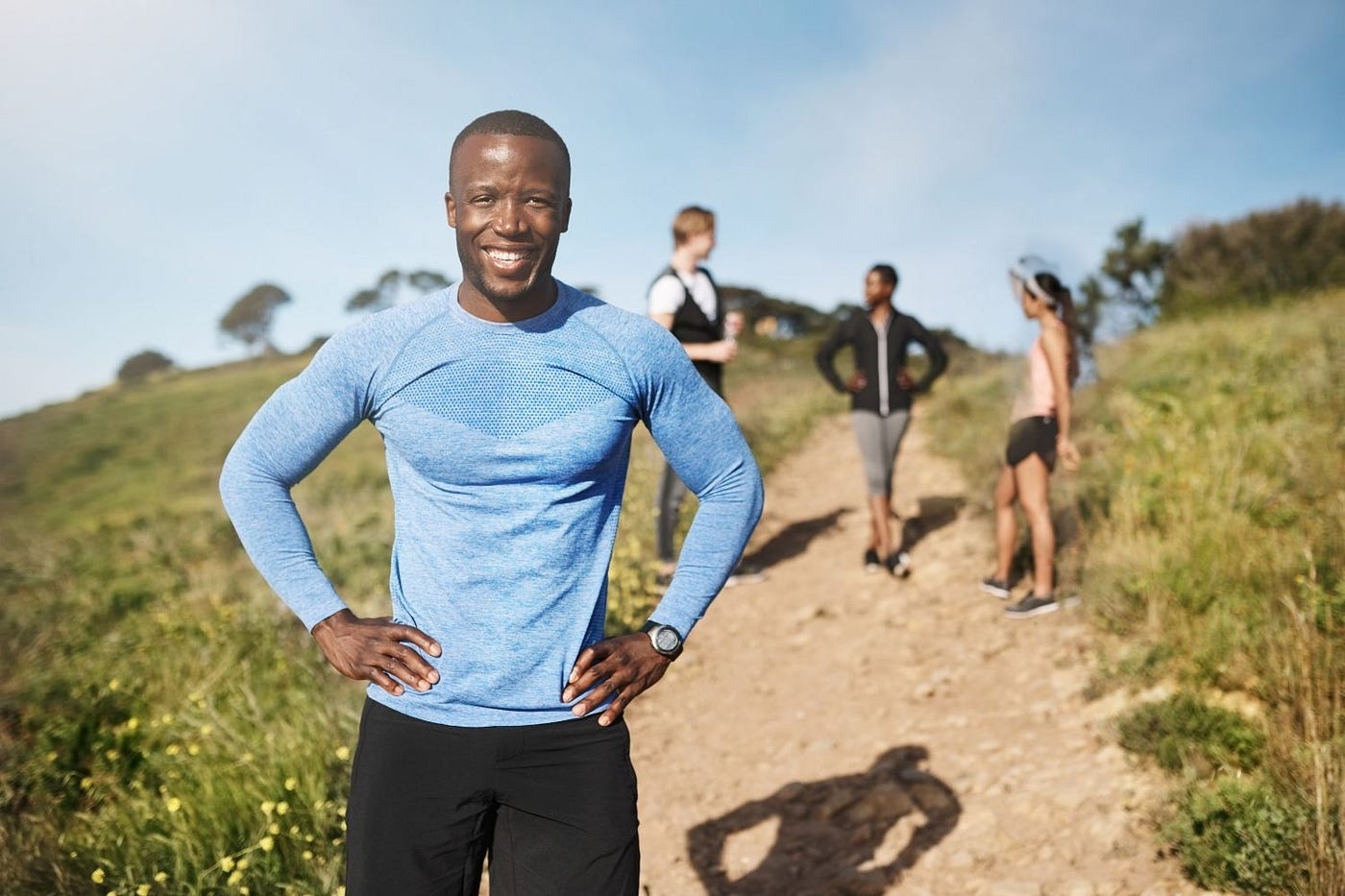 Man standing on walking trail with hands on hips smiling and happy.