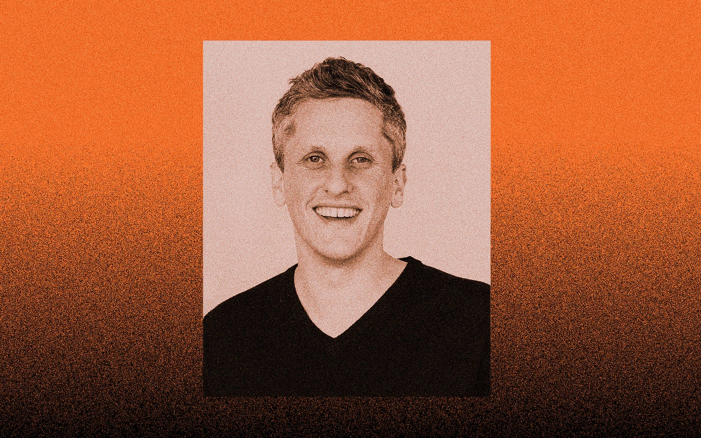 A photo of Aaron Levie against an orange gradient to black background.
