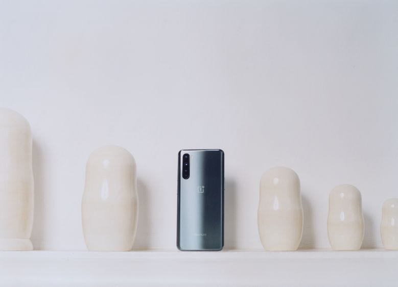 A promotional photo of a OnePlus Nord phone against a wall with cream-colored ceramics.