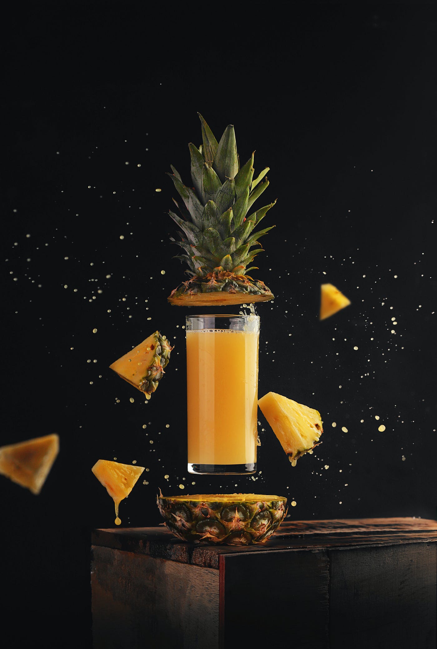 A pineapple sliced in two with a glass of juice in the middle.