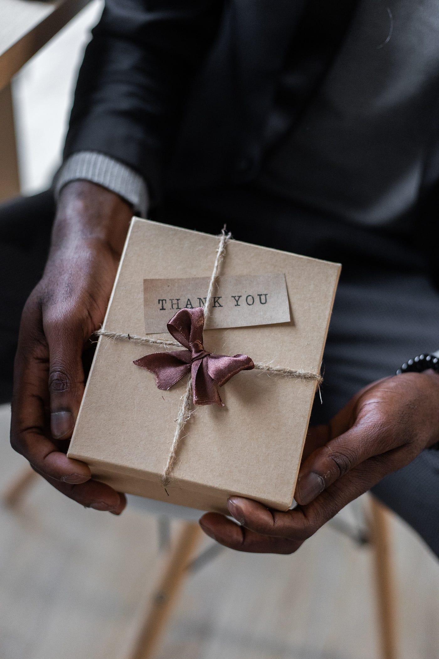 A man in a suit holding out a than you gift