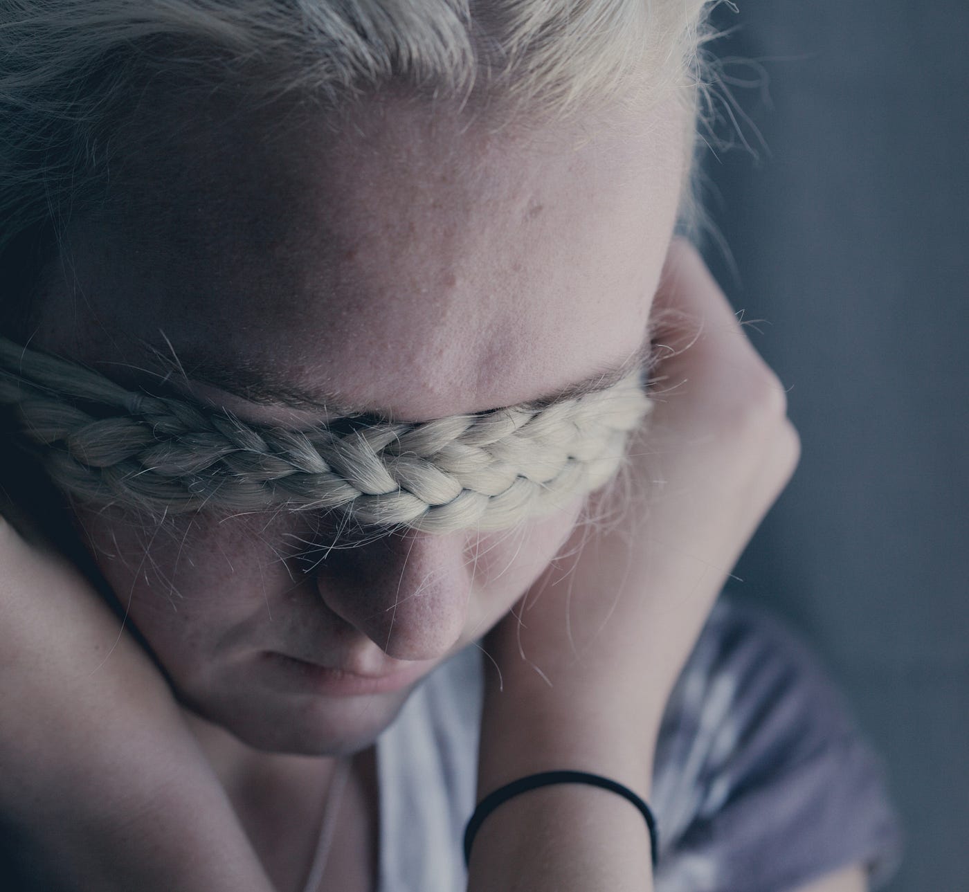 depressed-looking blonde with a braid wrapped over her eyes