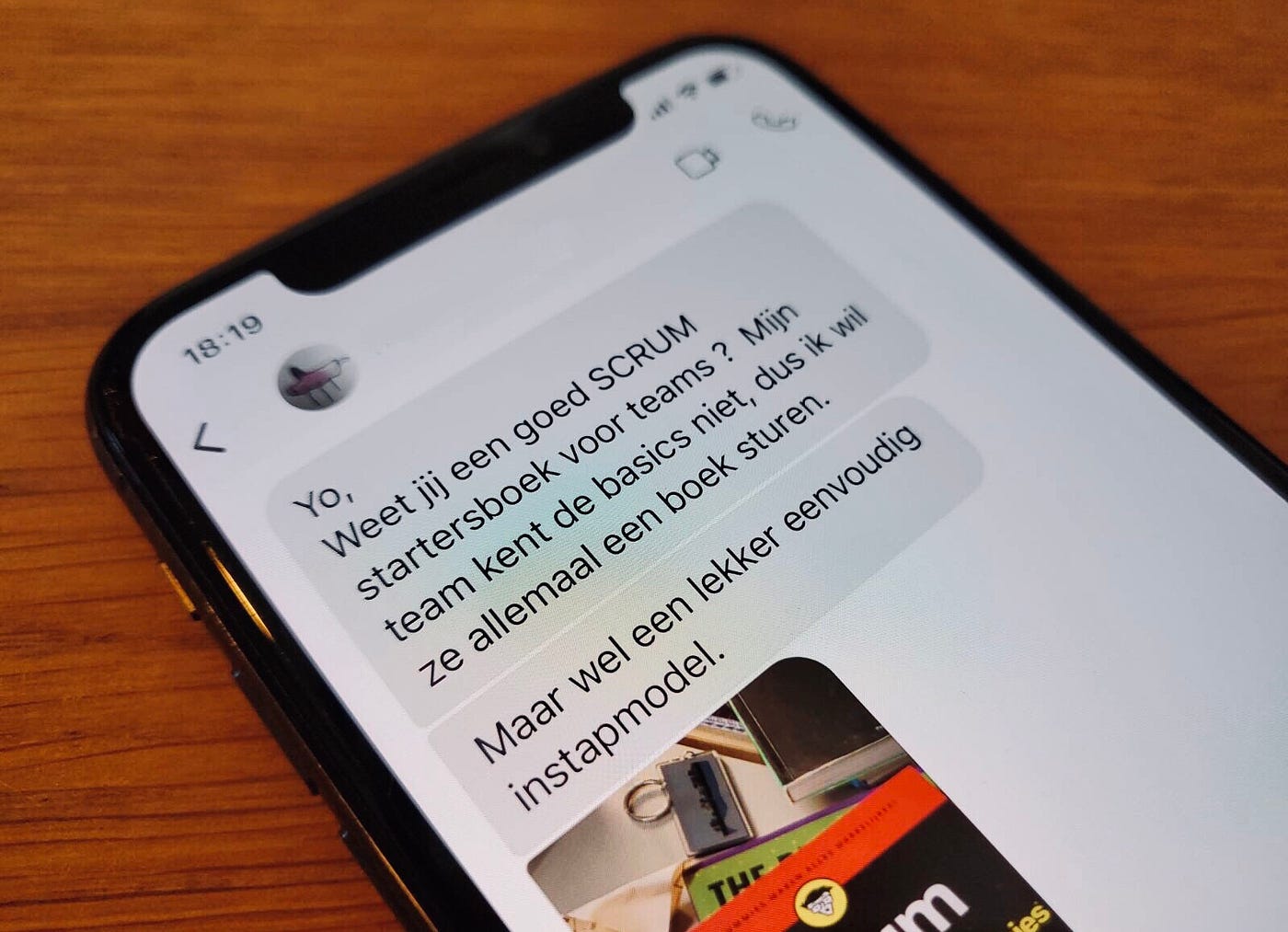 Dutch-language chat messages about Scrum books, displayed on the screen of the author’s iPhone, atop a wooden table