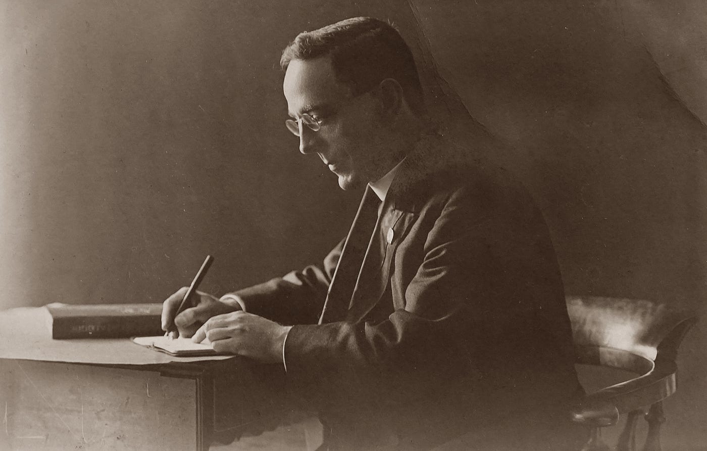 Black and white, old photo of a man’s side profile, writing a letter