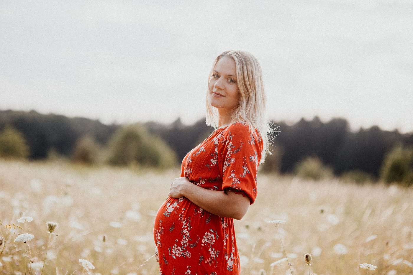 Pretty pregnant woman in red dress with protruding belly.