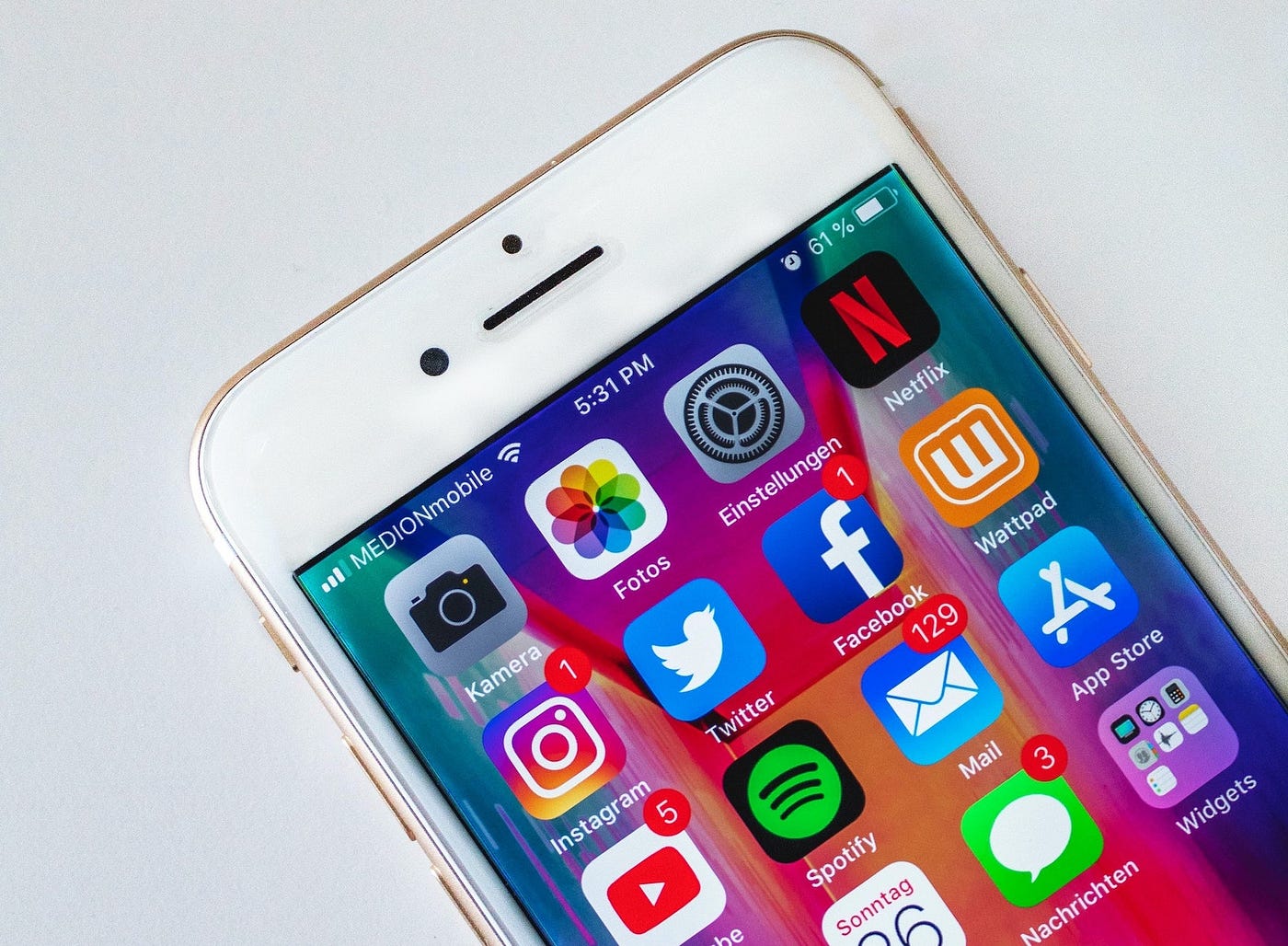 Image of white Iphone with apps on screen.