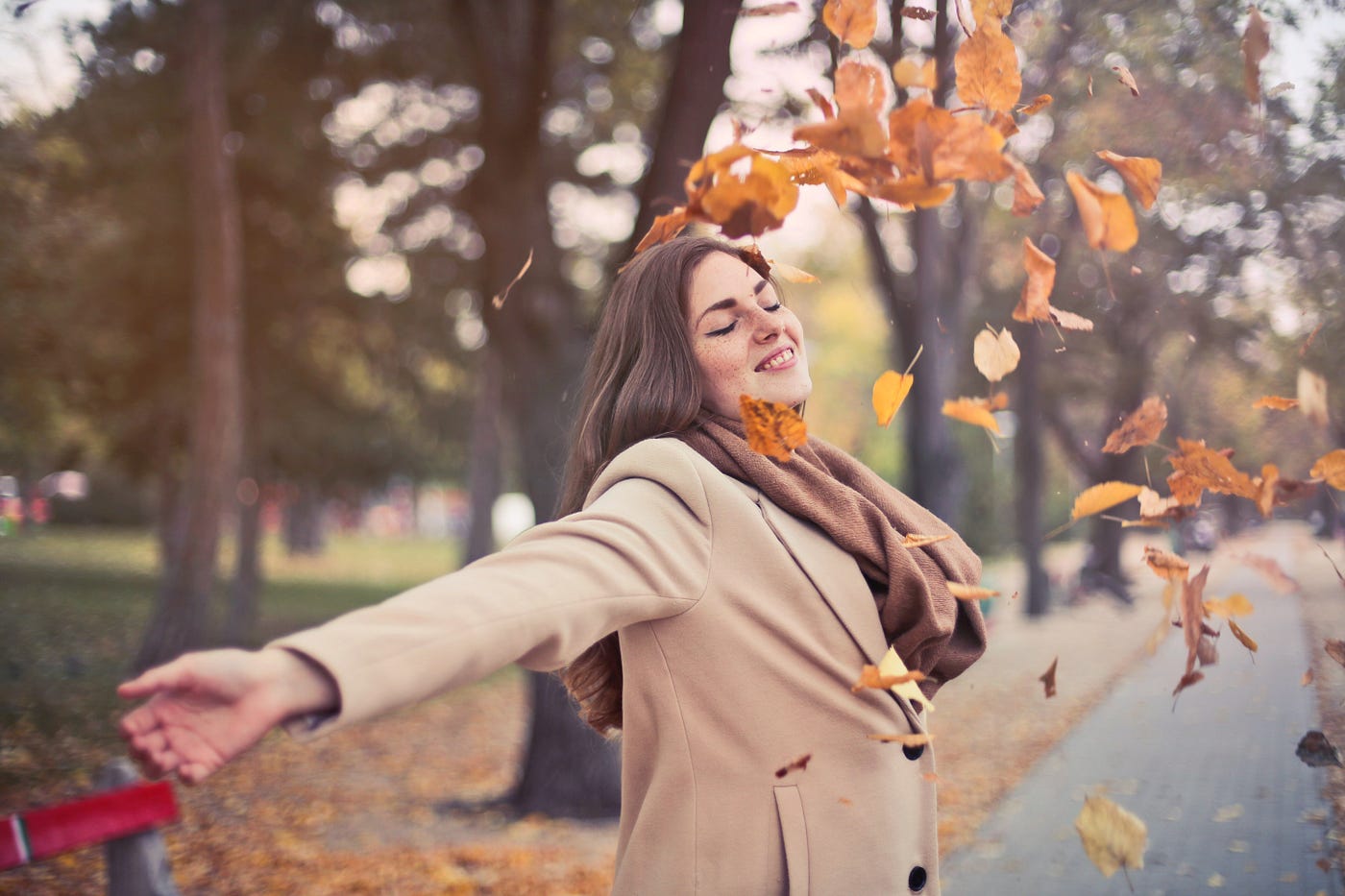 Woman In Brown Coat dancing with fall leaves.