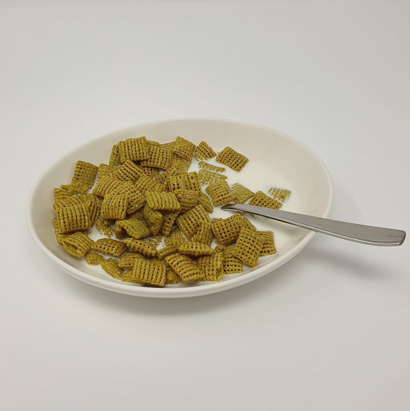 A finished bowl of Kellogg’s Chex Green Onion Cereal (Limited Edition) with milk and spoon.
