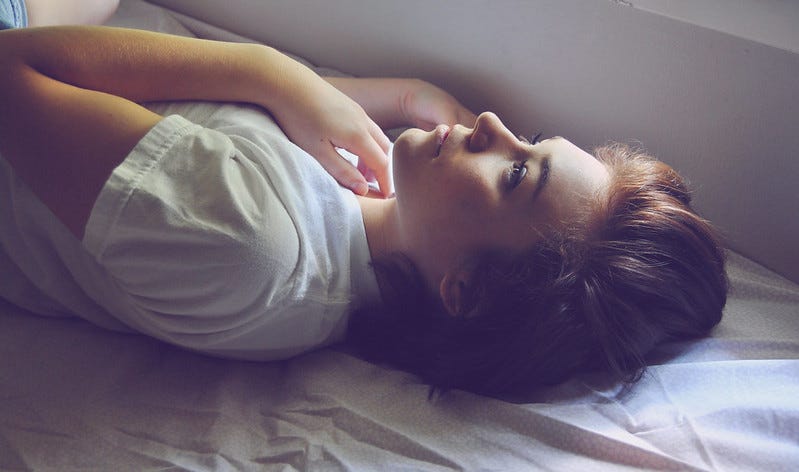 Woman lying in bed, staring up at the ceiling.