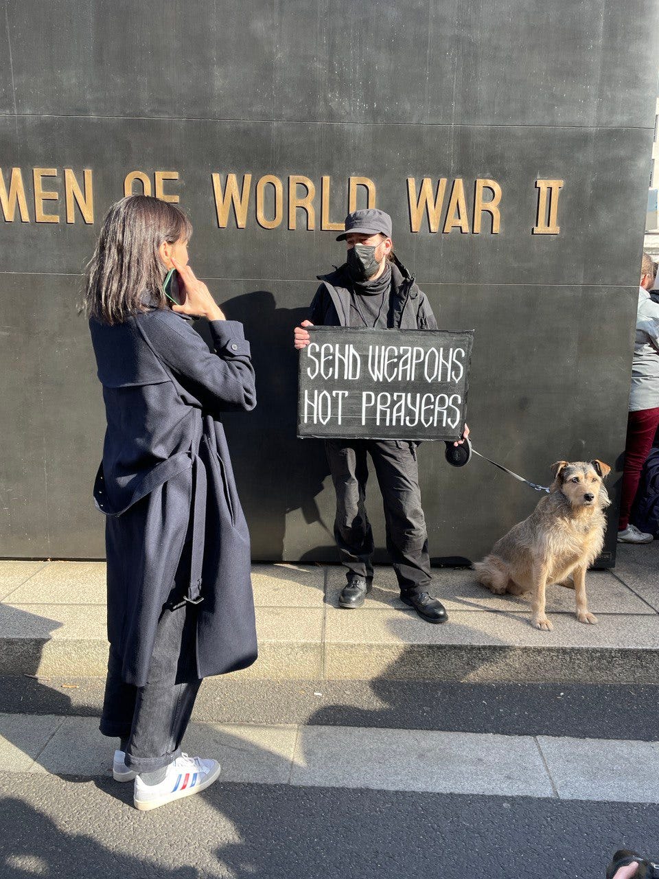 A man protesting in London, UK. His banner says “Send weapons, not prayers”