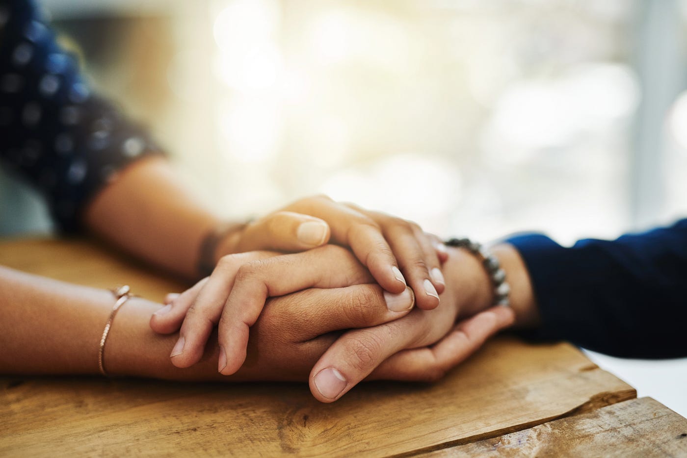 A closeup shot of two unrecognizable people holding hands in comfort. 