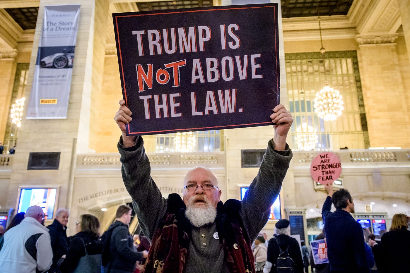 A protestor holds a sign that says “Trump is NOT above the law.”