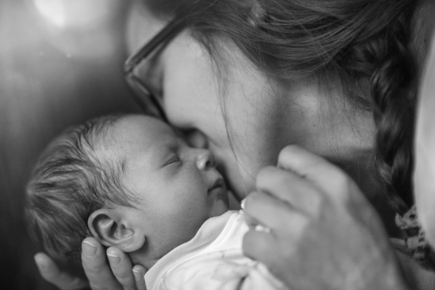 Black and white photo of a mother kissing her infant.