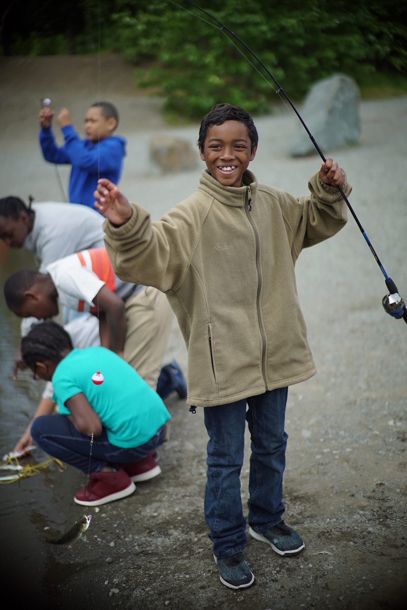 boy holding a small fish with a group of kids behind him