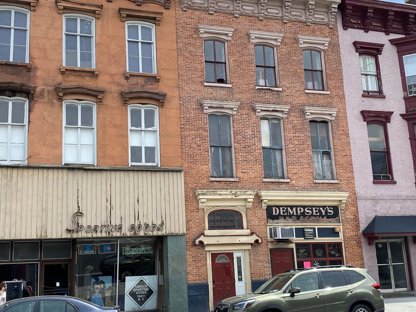 Pre-war brown brick buildings in downtown Troy, with vintage 1960s signage