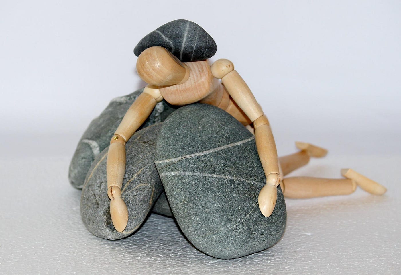 wooden human figure being crushed by rocks