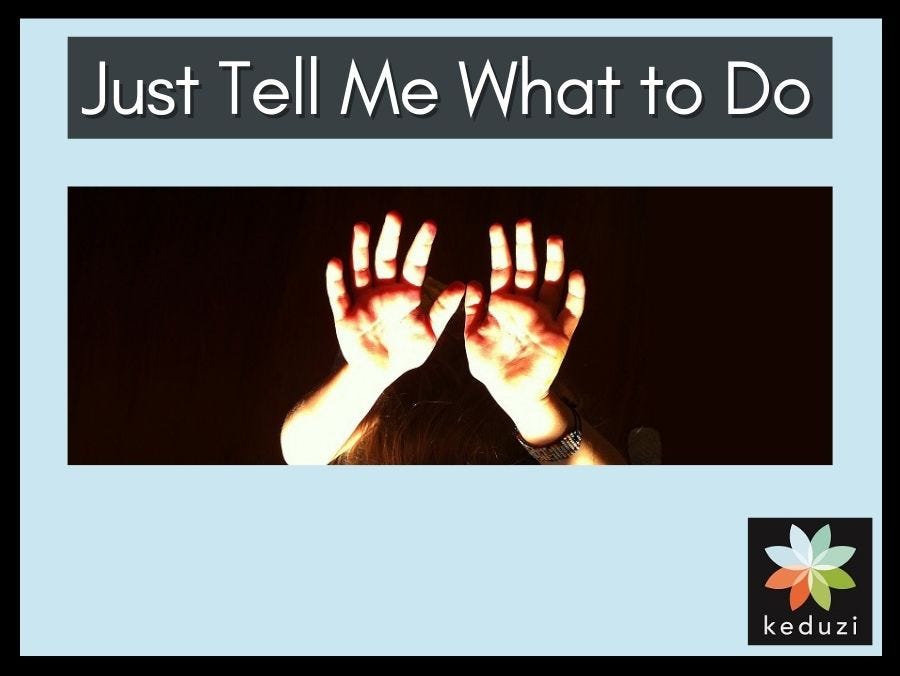 A child’s hands are raised up and lit up against a dark backdrop. You can barely see the top of a head and a bracelet on one wrist. The words over the image are “Just Tell Me What to Do”. The Keduzi logo, which is a colourful flower, is also over the image.