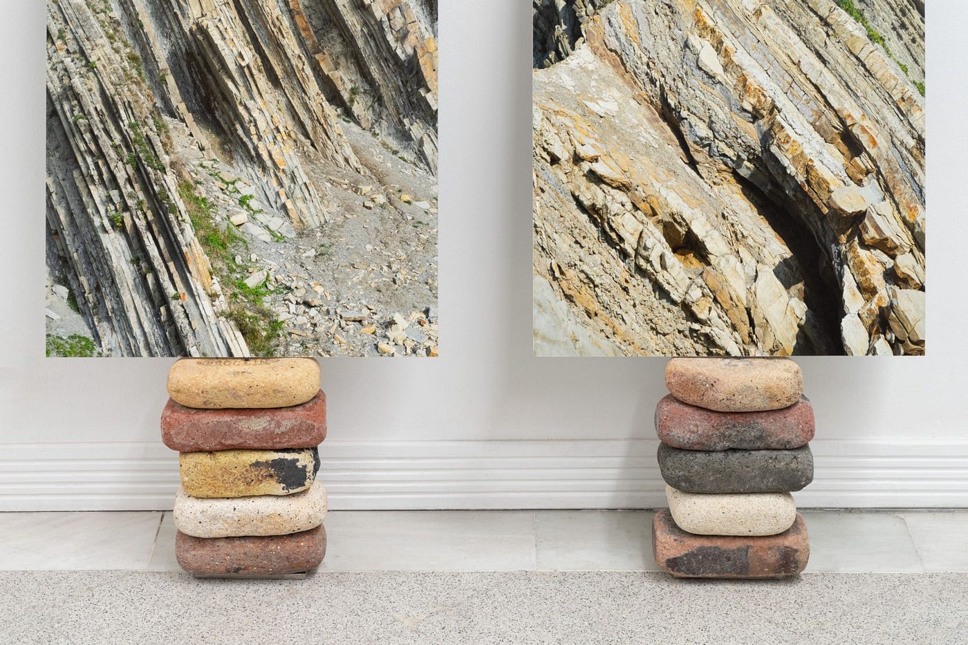 Two totems made of bricks and site-specific materials. They look like two piles of bricks and rocks of different colors with a picture of geological formations on top of each pile.