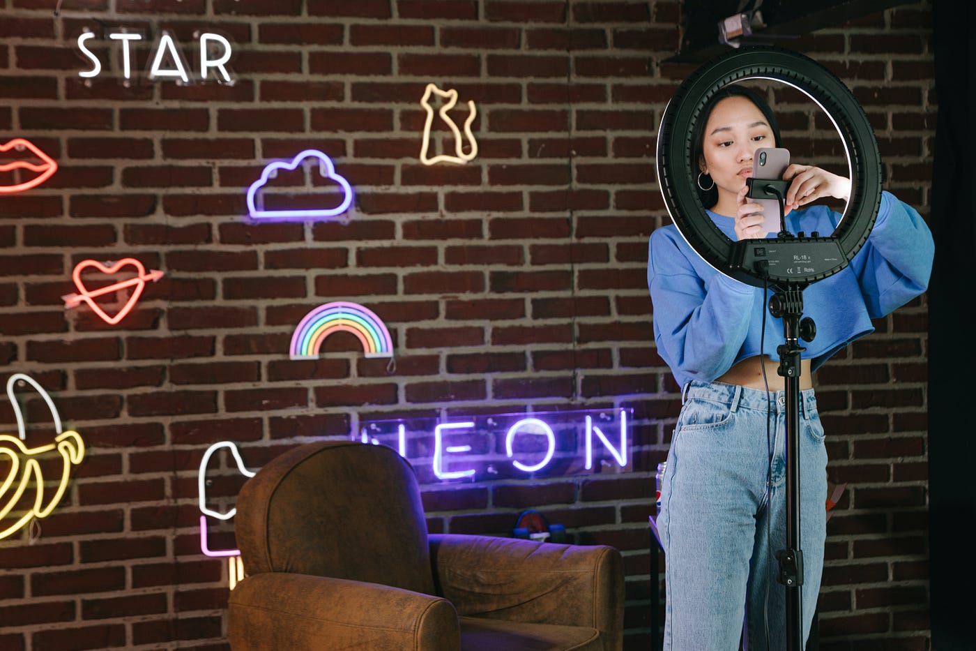woman standing in front of circle light with her phone
